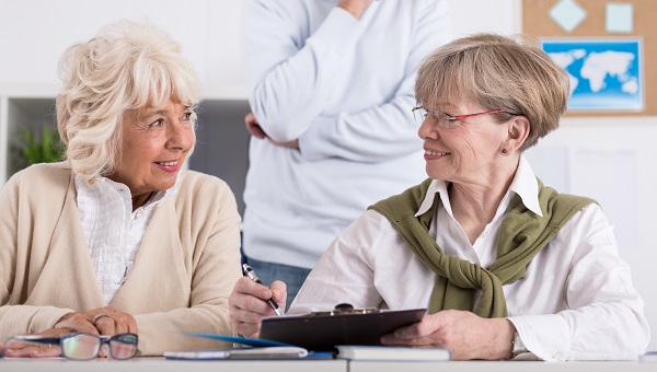 two elderly women filling out form on clipboard