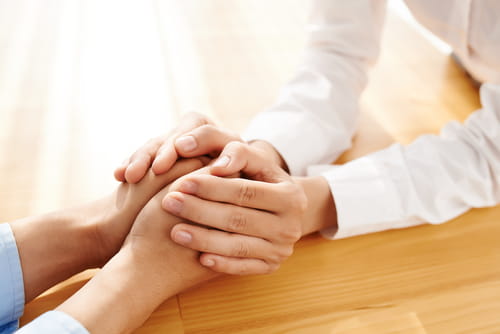 One person's hands holding the hands of another person.