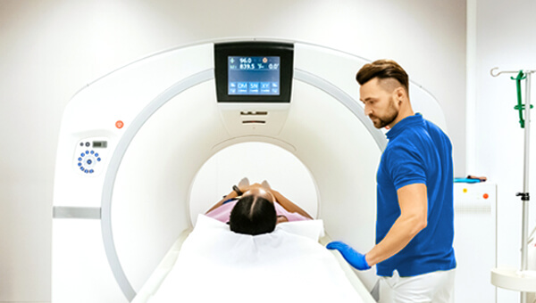 A male medical technician preparing a patient for an MRI scan