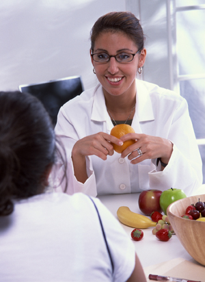 Nutritionist holding fruit while talking with client.