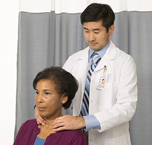 Doctor feeling woman's neck to examine thyroid.