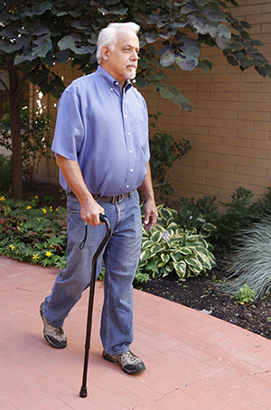 Man with cane walking outdoors.