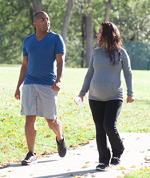 Man and pregnant woman walking in park.