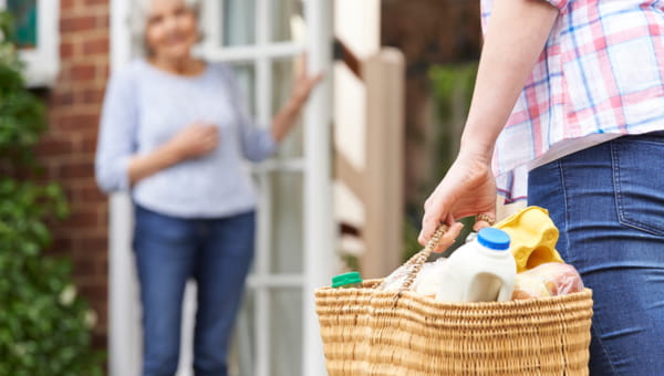 A senior woman is getting a delivery of groceries.