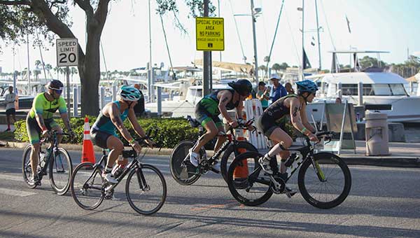 four cyclists racing down a street near the water