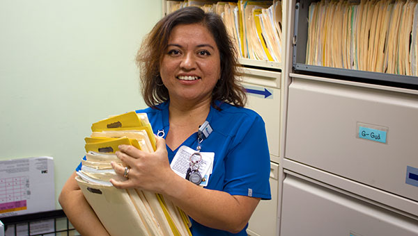 female care professional in baycare blue scrubs holding a stack of files