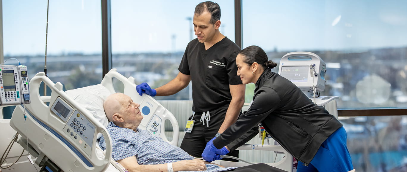 Two BayCare providers standing at the bed of a cancer patient.