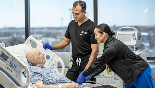 Image of a doctor and a nurse caring for a cancer patient in their hospital bed