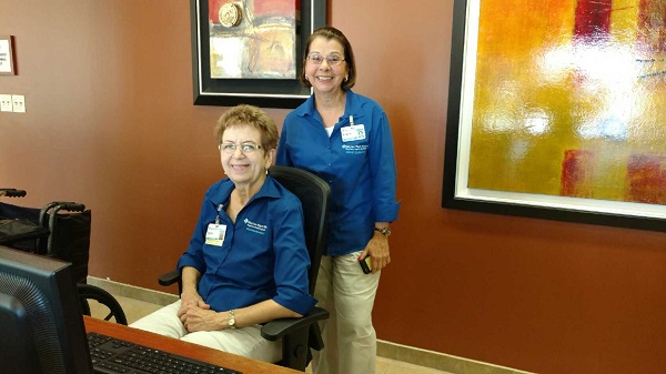 Two BayCare volunteers working at a hospital reception desk