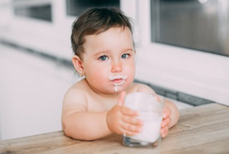 A little girl in the kitchen drinking milk 
