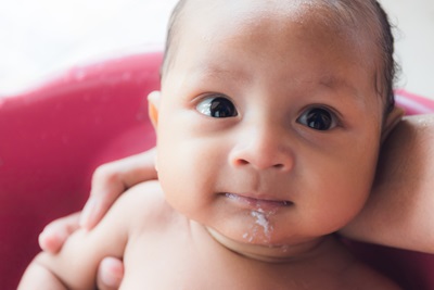 A baby has spit up some milk on his chin.