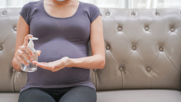 pregnant woman sitting on couch with dispenser