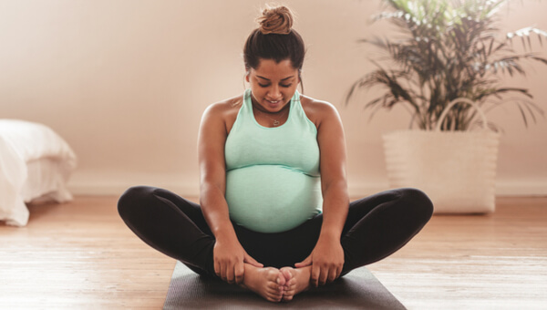 pregnant woman sitting on floor and holding her feet