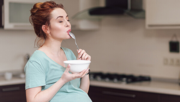 a woman eating from a bowl with a spoon held to her mouth