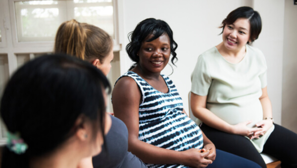 a smiling pregnant woman sitting with her friends