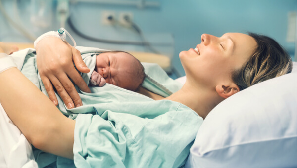 a woman and her newborn laying on a hospital bed