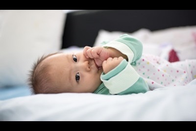 beautiful newborn baby girl is laying down sucking her thumb