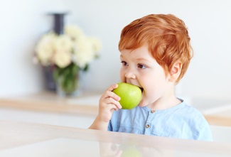 cute redhead toddler baby biting tasty green apple