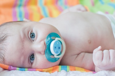 Little baby with blue soother lays