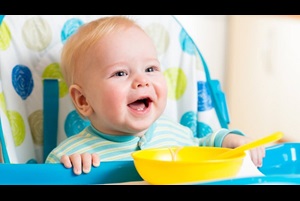 smiling baby eating food from a high chair
