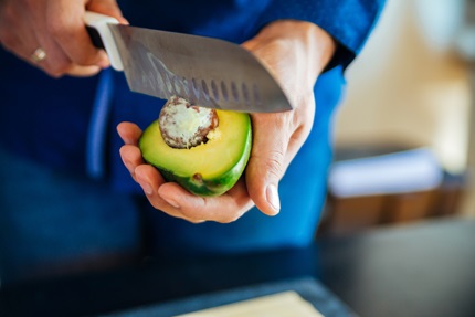 A man is not being careful while cutting an avocado.