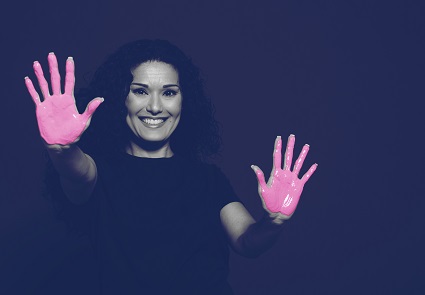 A woman is showing the palms of her hands, which are painted pink.