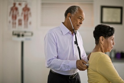 Mature male physician listening to a female patient's lungs