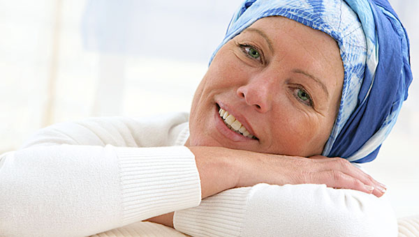A female cancer survivor is wearing a blue and white scarf on her head.