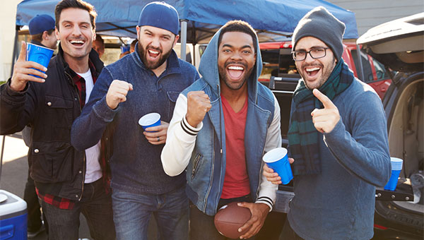A group of male friends are tailgating before a football game.