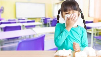 Little girl in a classroom, blowing her nose