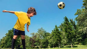 A soccer ball bounces off the head of a boy playing soccer.