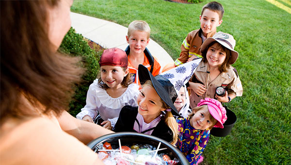 A group of costumed children goes trick-or-treating in a neighborhood.