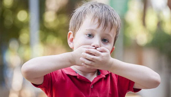 A child holding his mouth while he has the hiccups