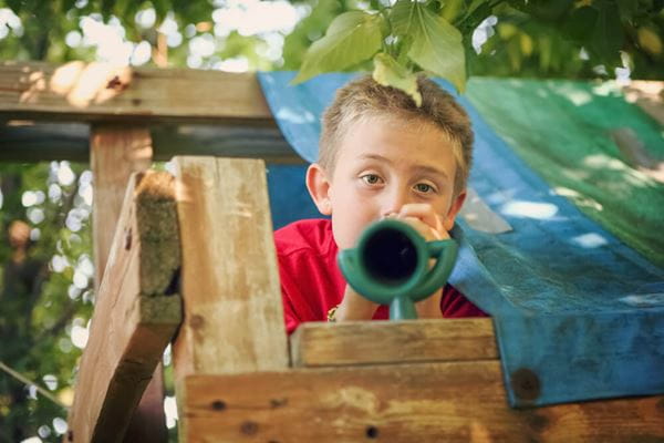 boy in a tree house using a toy telescope