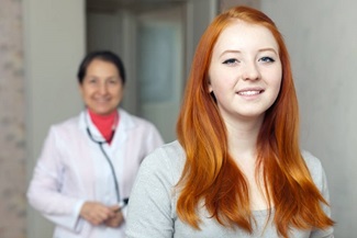 red haired female child standing with a physician