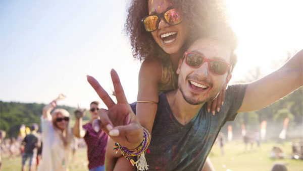 A young couple is wearing sunglasses at an outdoor festival.
