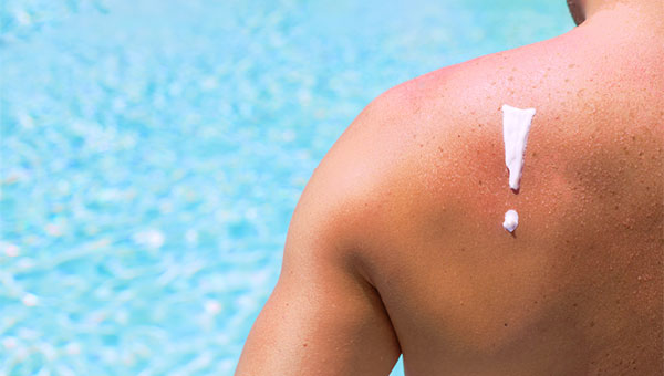 A man has sunscreen on his shoulder while at the pool.