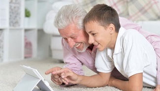 A grandfather and grandson are looking at a tablet device.