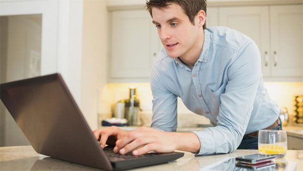 A young man is typing on his laptop.