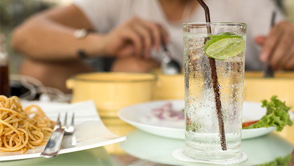 A woman has a carbonated beverage with her meal.