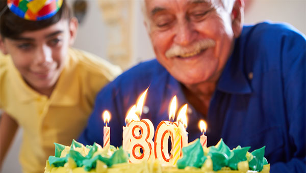 A grandfather is getting ready to blow out the candles on his birthday cake.