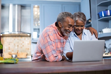 mature couple in a kitchen, looking at a laptop