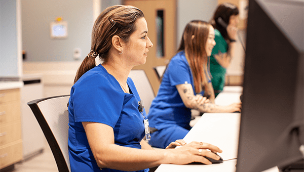 Female BayCare staff member sitting at her desk on the computer.