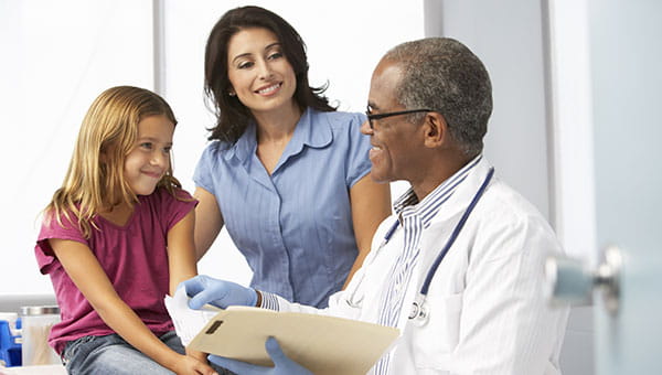 A mother and her young daughter talk with the doctor.