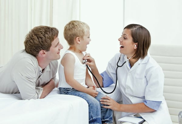 A  father is watching his young son get a check up from his pediatrician.