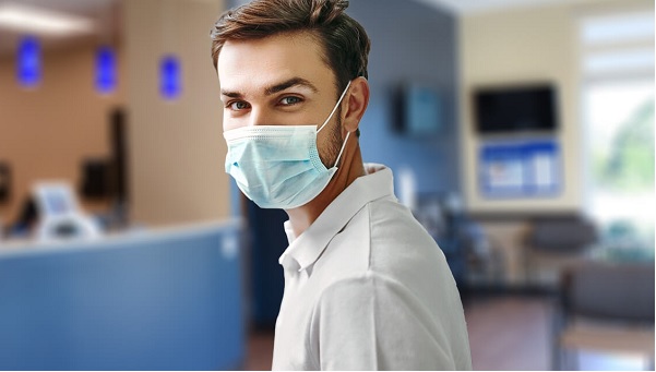 young male wearing a mask standing in an urgent care center