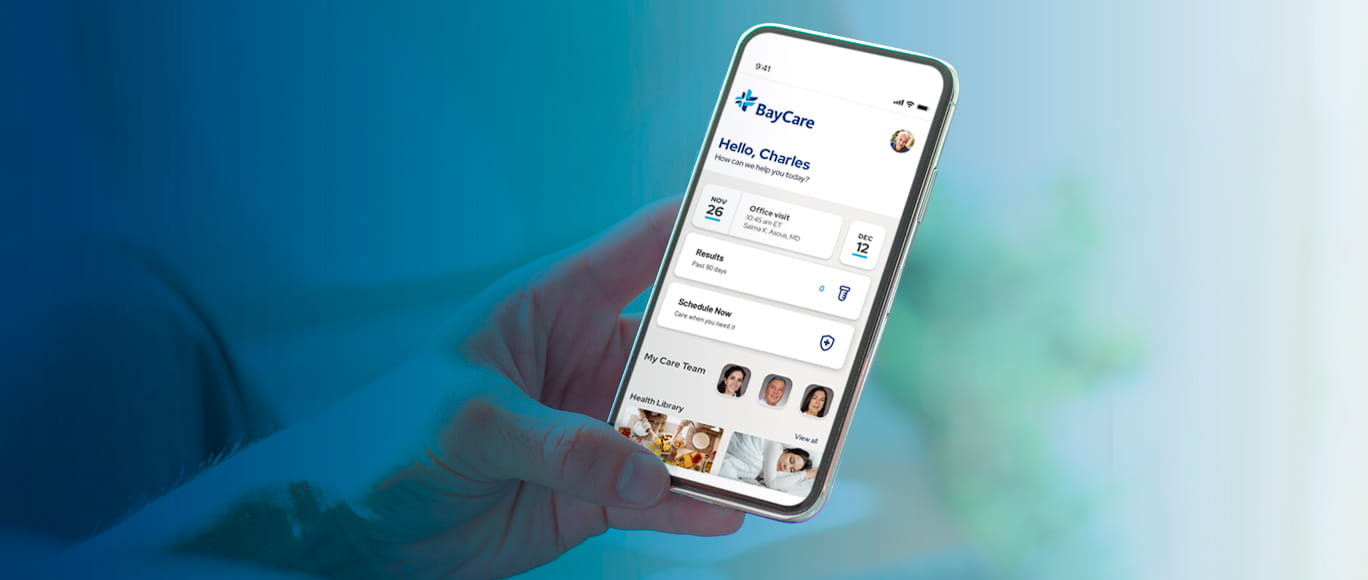 Image with blue overlay of a hand holding a mobile phone, displaying the BayCare App mobile experience.