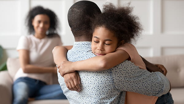 daughter hugging her father with her mother in the background