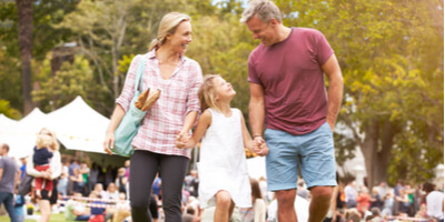 Two adults holding a child's hand at an outdoor event