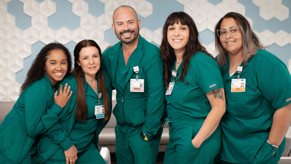 A group of nursing support staff in green scrub at a BayCare facility stands together for a photo.